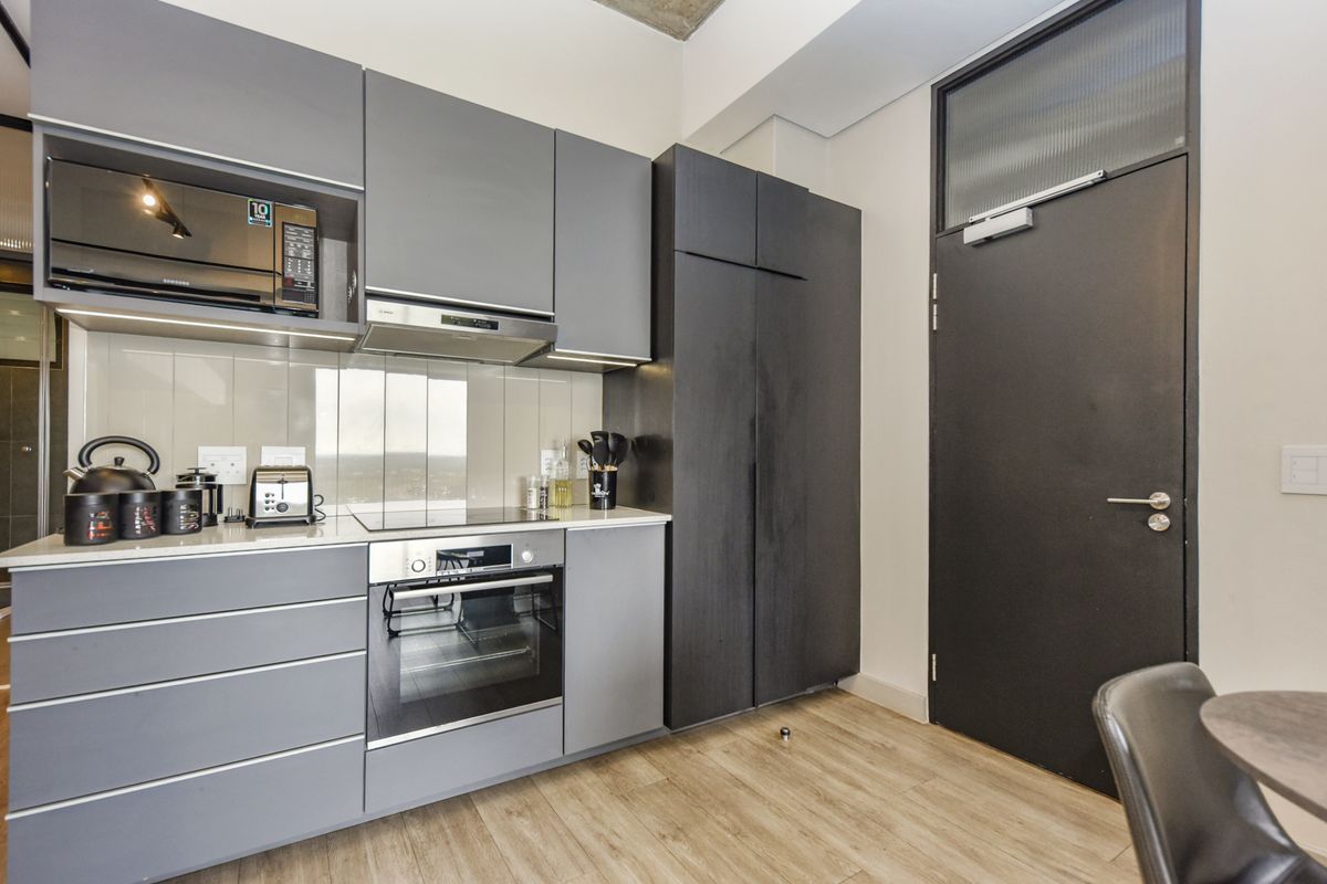Modern kitchen featuring sleek grey cabinetry, integrated appliances including an oven and hob, and high-quality finishes throughout.