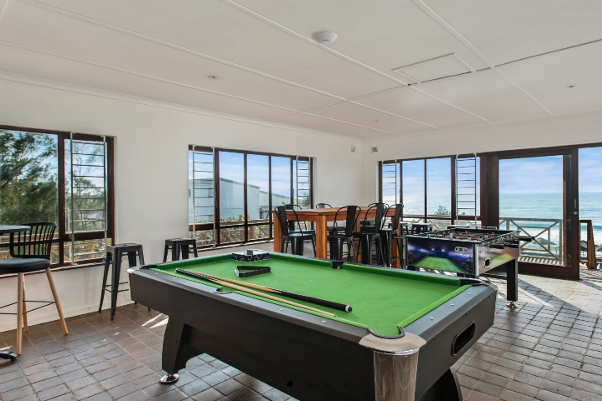 Spacious living area featuring tiled flooring, large windows, and sliding glass doors that offer expansive ocean views and natural light.