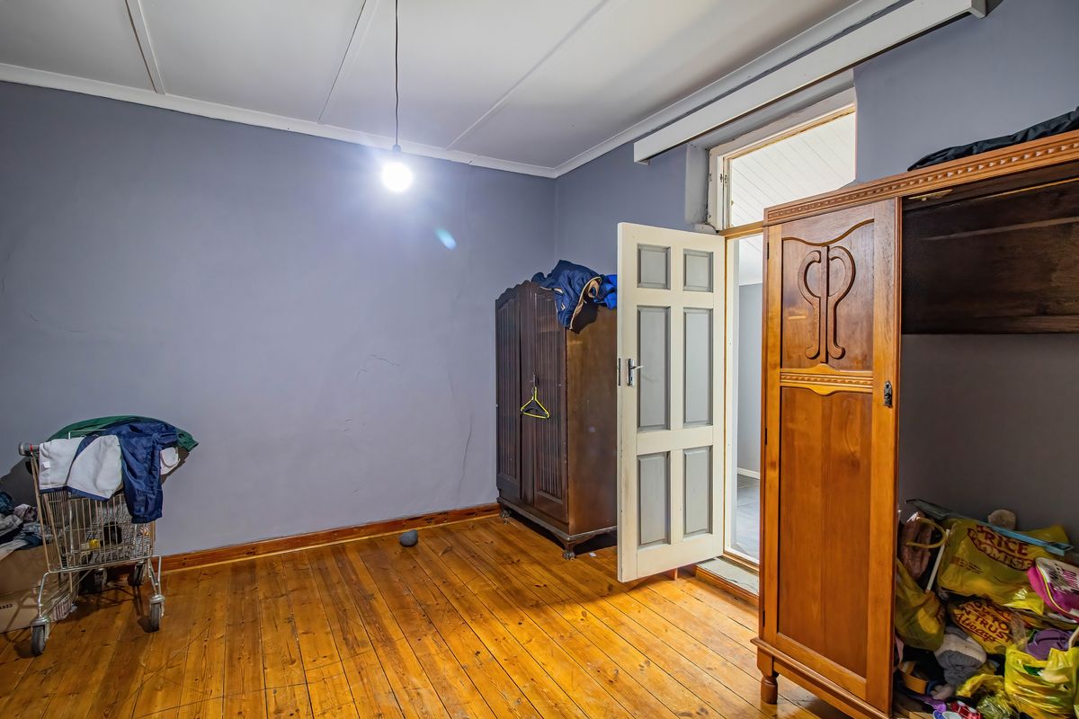 A bedroom featuring original timber flooring and a panelled door, requiring cosmetic updates to the wall finishes.