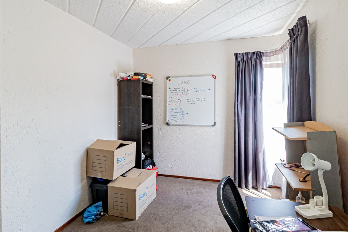 A bedroom featuring carpet flooring and a textured ceiling, offering a functional space with natural light from the window.