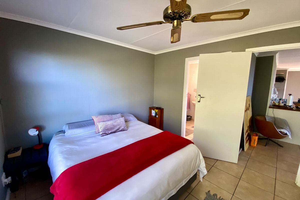 A bedroom featuring tiled flooring, a ceiling fan, and direct access to an en-suite bathroom.