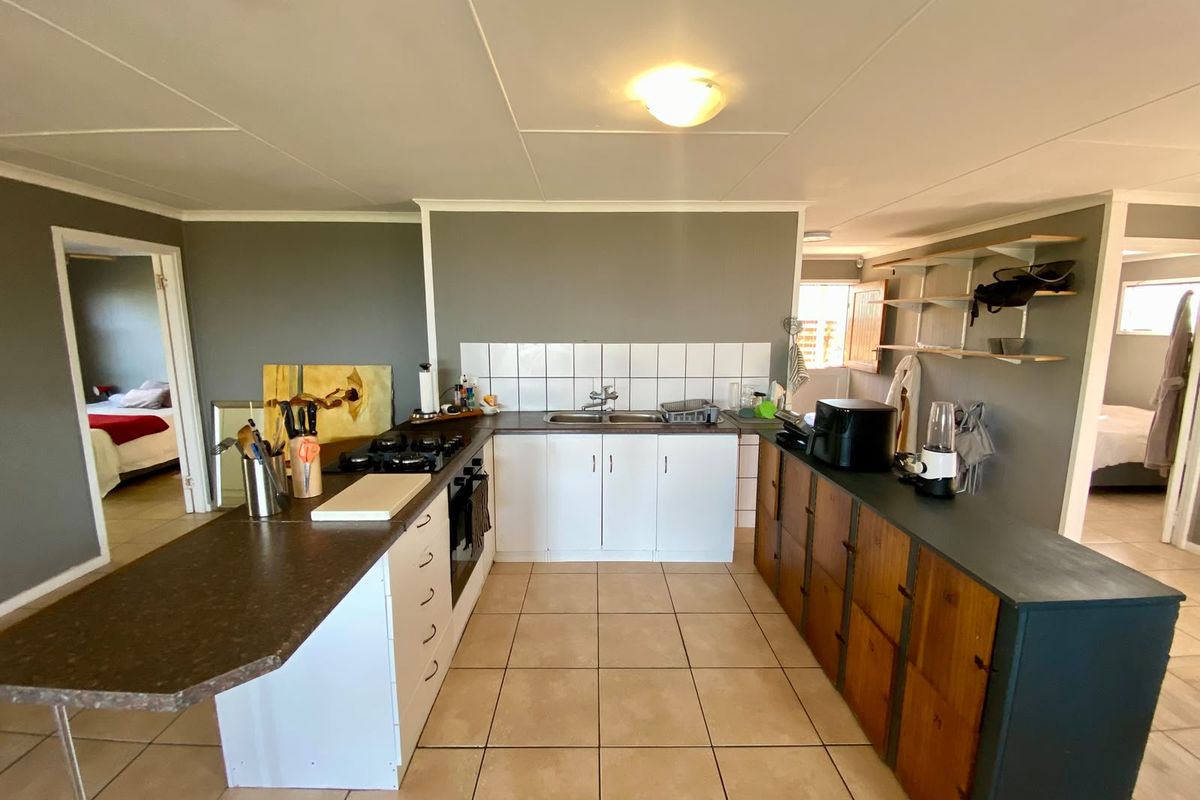 Functional kitchen featuring a gas hob, built-in oven, double basin sink, and a mix of white and wood-toned cabinetry with tiled flooring.