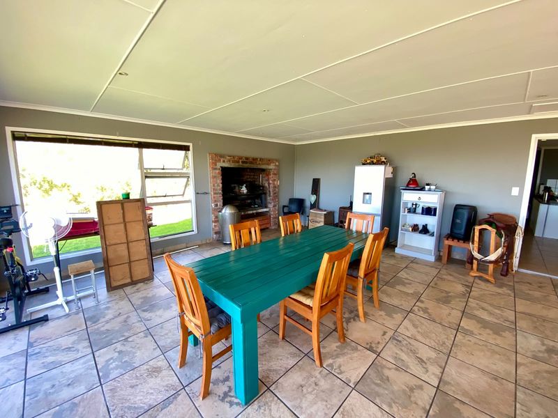 Spacious dining area featuring tiled flooring, a built-in brick fireplace, and large windows providing natural light.