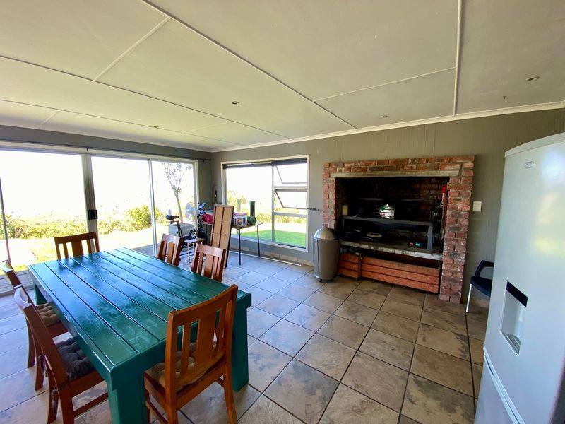 Enclosed patio area featuring a built-in brick braai, tiled flooring, and large sliding glass doors providing access to the garden.