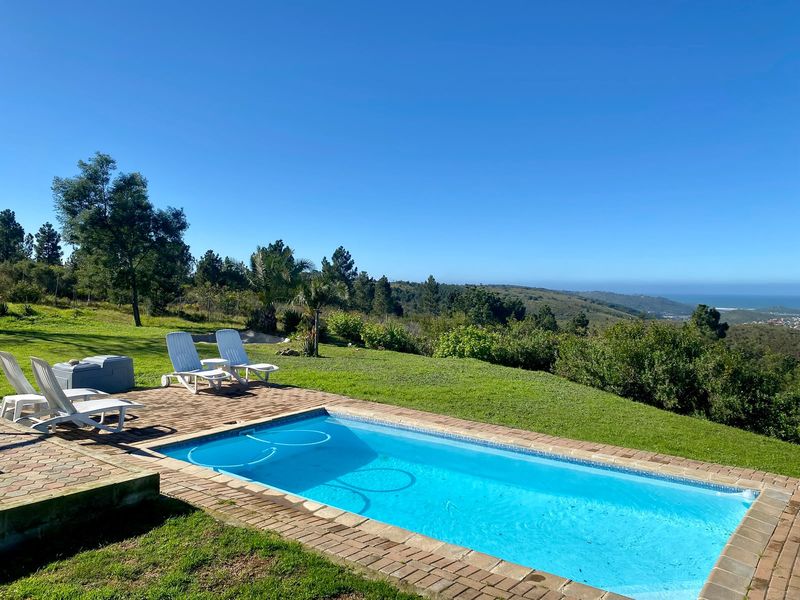 Outdoor swimming pool area featuring brick paving and expansive views of the surrounding landscape and distant coastline.