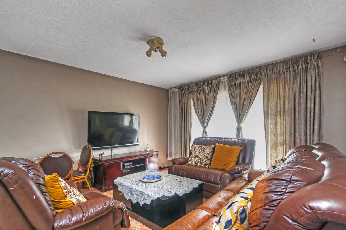 A living room featuring neutral wall tones, large window with curtain tracks, and a central ceiling light fixture.