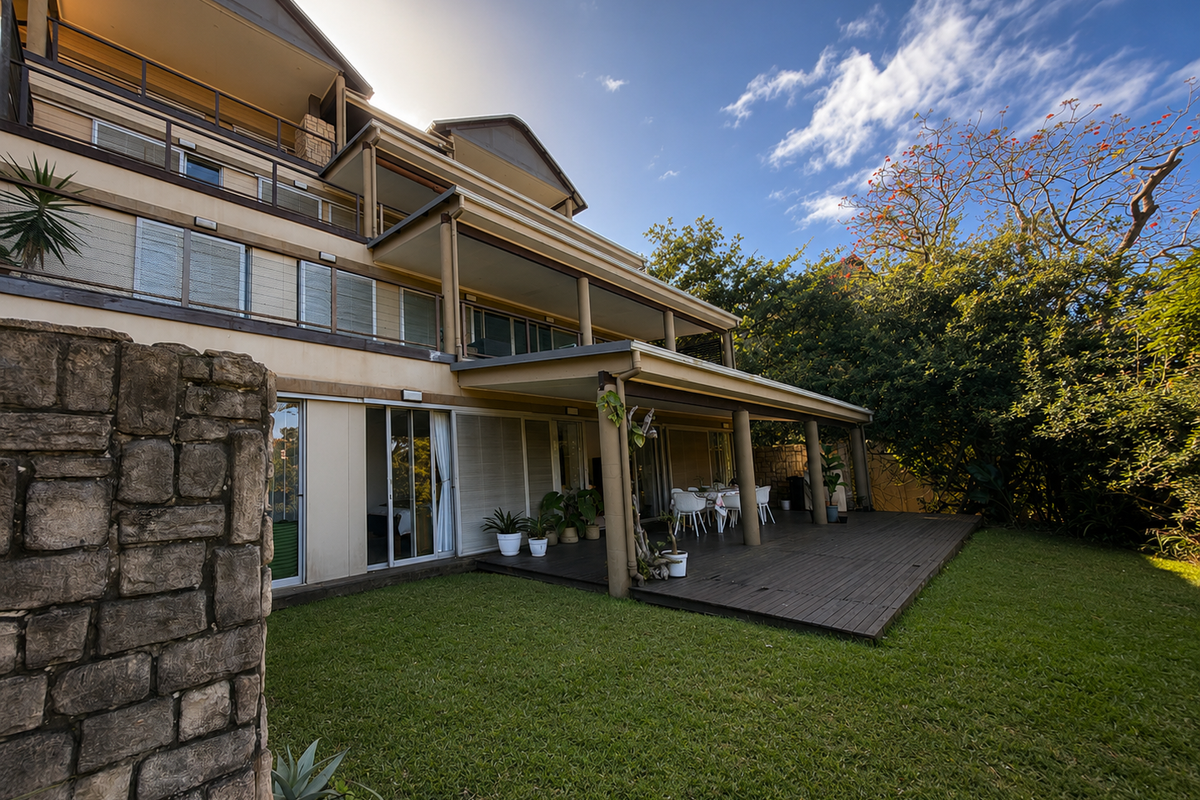 Rear view of the apartment building featuring a spacious timber deck, landscaped garden, and multiple levels of balconies with sliding glass door access.