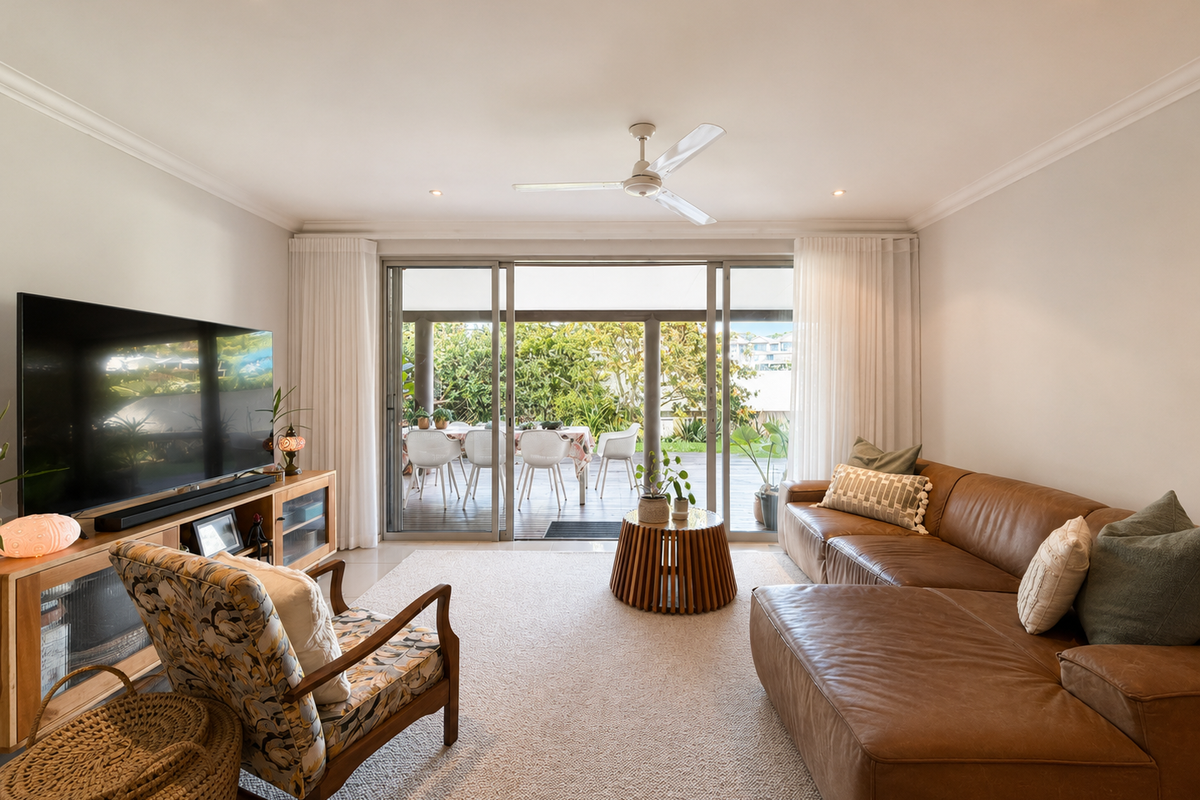 A bright and inviting living room featuring recessed lighting, a ceiling fan, and large sliding glass doors that open onto an outdoor patio area.