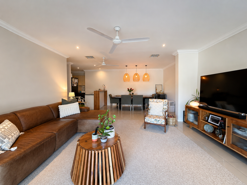 Spacious open-plan living and dining area featuring tiled floors, ceiling fans, and a functional kitchen island, creating a bright and cohesive living space.