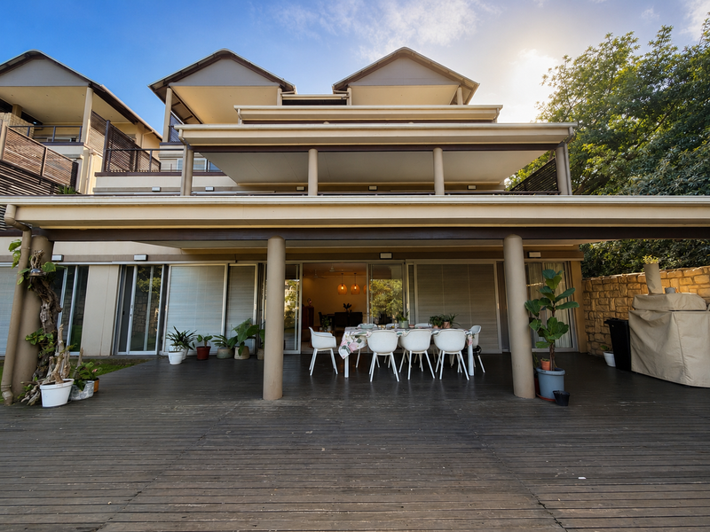 Spacious covered timber deck patio featuring structural columns and direct access to the interior through large sliding glass doors.