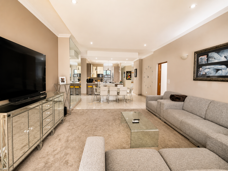 Spacious open-plan living and dining area featuring neutral tones, recessed lighting, tiled kitchen flooring, and a seamless transition to the kitchen space.