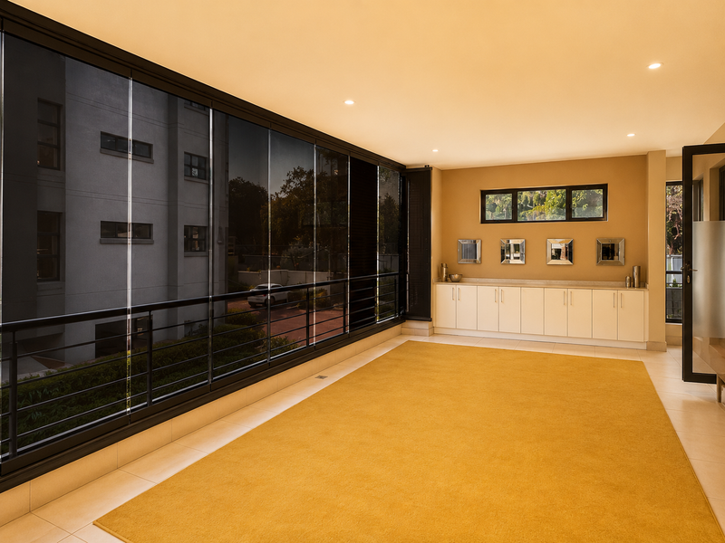 A spacious, enclosed balcony featuring tiled flooring, built-in cabinetry, and large glass panels offering a bright, versatile living space.