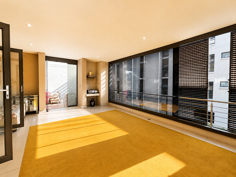 Spacious enclosed balcony featuring large glass sliding doors, tiled flooring, and recessed lighting, offering a bright and versatile indoor-outdoor living space.