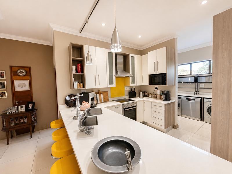 Modern open-plan kitchen featuring a large island with quartz countertops, integrated appliances, and a seamless transition to a functional scullery area.