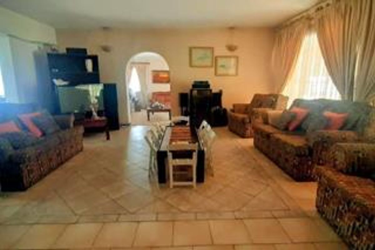 Spacious living area featuring tiled flooring and an arched entryway leading to an adjacent room, offering a functional and open layout.