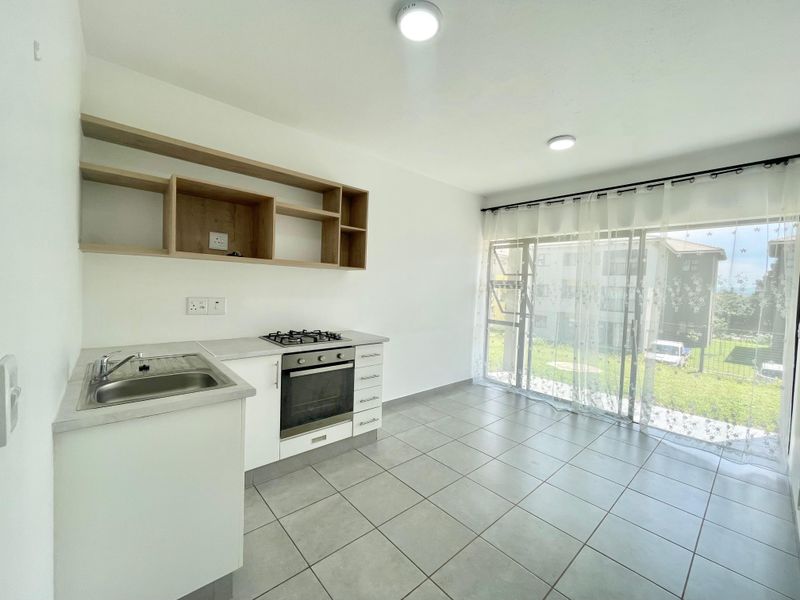 Bright open-plan kitchen and living area featuring modern cabinetry, built-in oven, gas hob, and large sliding doors leading to the exterior.