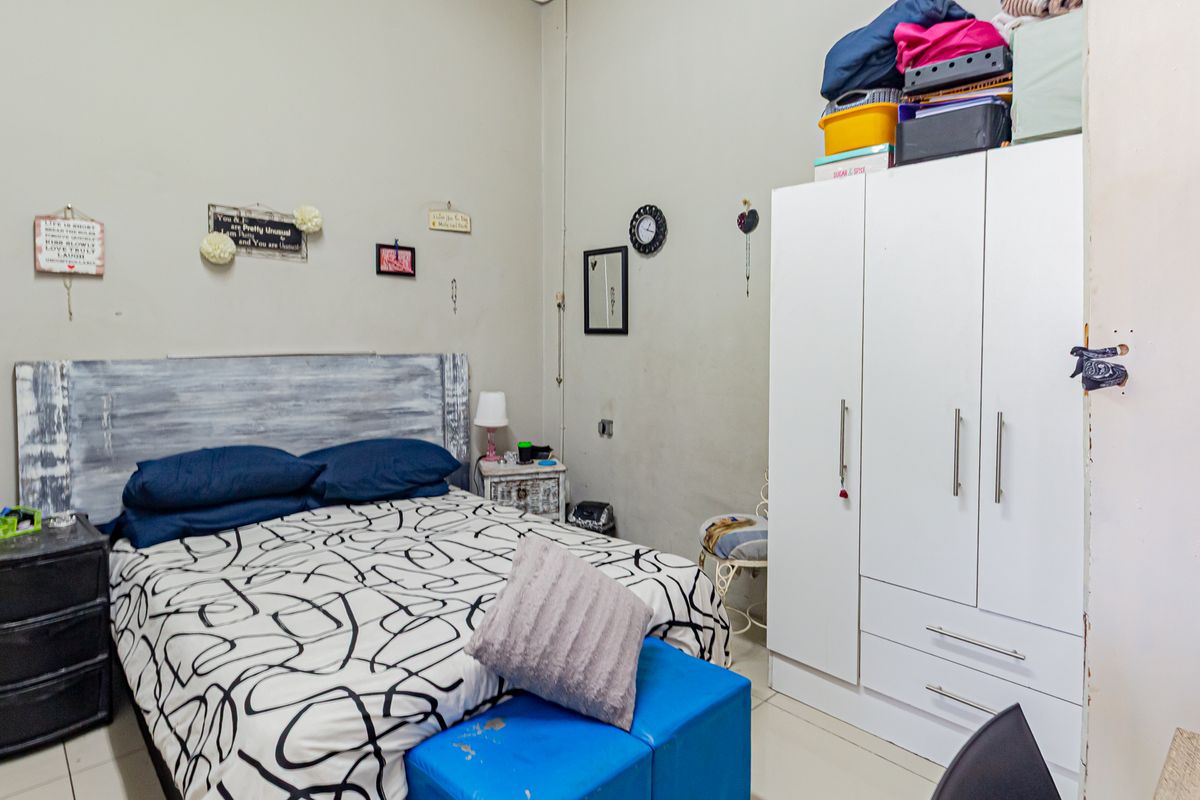 A bedroom featuring tiled flooring and a built-in white wardrobe, offering a functional space with potential for cosmetic updates.