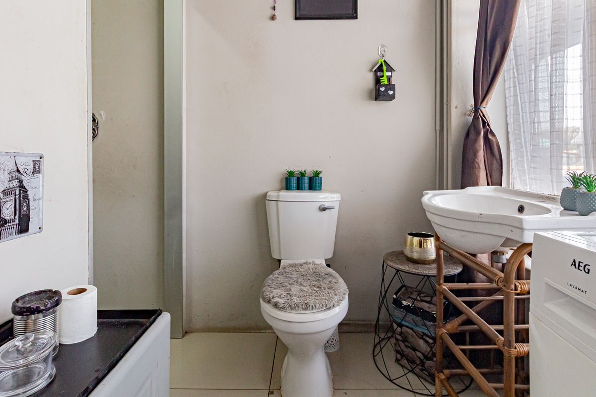 A functional bathroom featuring a standard toilet and pedestal basin with tiled flooring, offering a practical layout for an apartment setting.