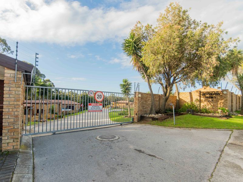 The secure entrance to Kingston Mews featuring a gated access point, brick boundary walls, and electric fencing for added security.