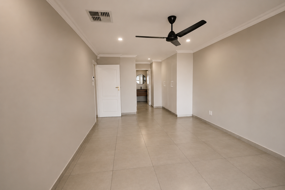 Spacious bedroom featuring neutral tiled flooring, built-in cupboards, a ceiling fan, and ducted air conditioning, with an adjoining ensuite bathroom visible.
