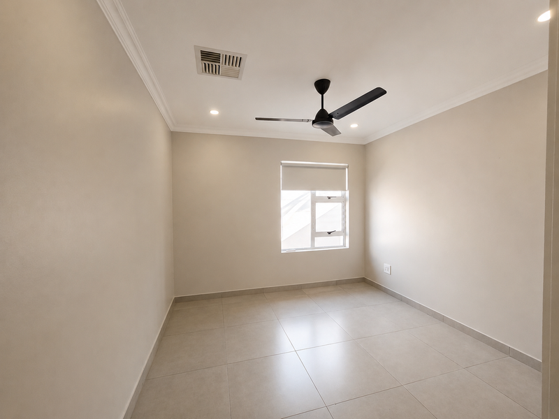 A clean, neutral-toned bedroom featuring tiled flooring, a ceiling fan, and ducted air conditioning, offering a blank canvas for personalization.