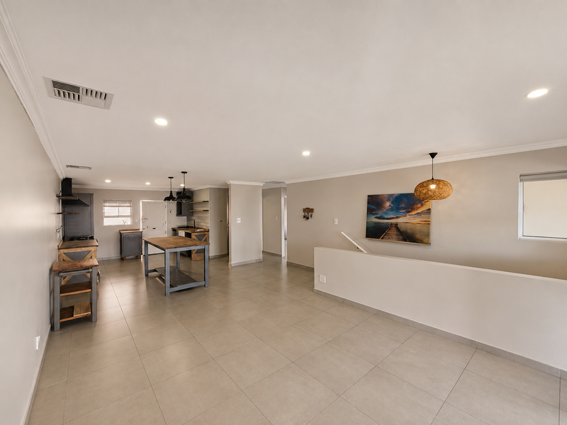 Spacious open-plan living and kitchen area featuring neutral tiled flooring, recessed lighting, and modern built-in cabinetry with a functional layout.
