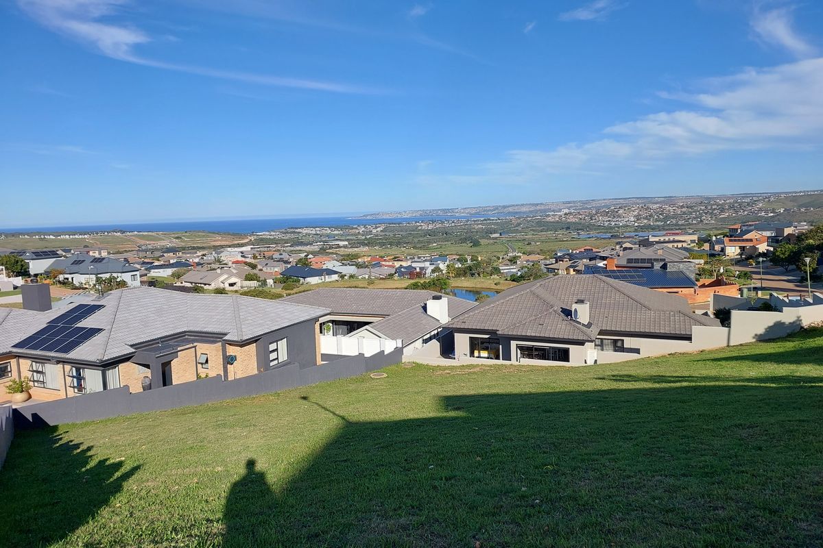 Elevated view overlooking a residential neighborhood with coastal scenery in the distance, showcasing the surrounding landscape and community layout.
