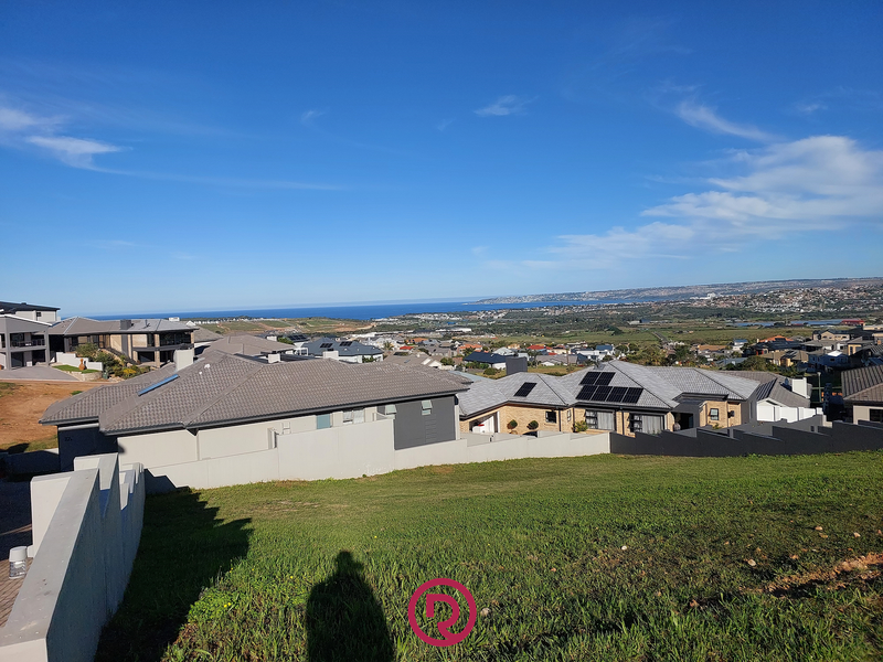 Elevated view overlooking a residential neighborhood with a clear coastal horizon and ocean backdrop.