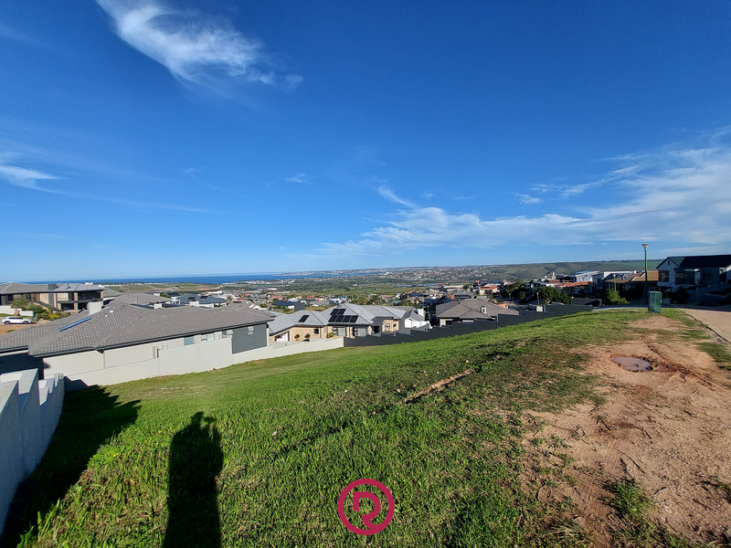 A wide-angle view overlooking a residential estate with distant coastal scenery and clear blue skies.