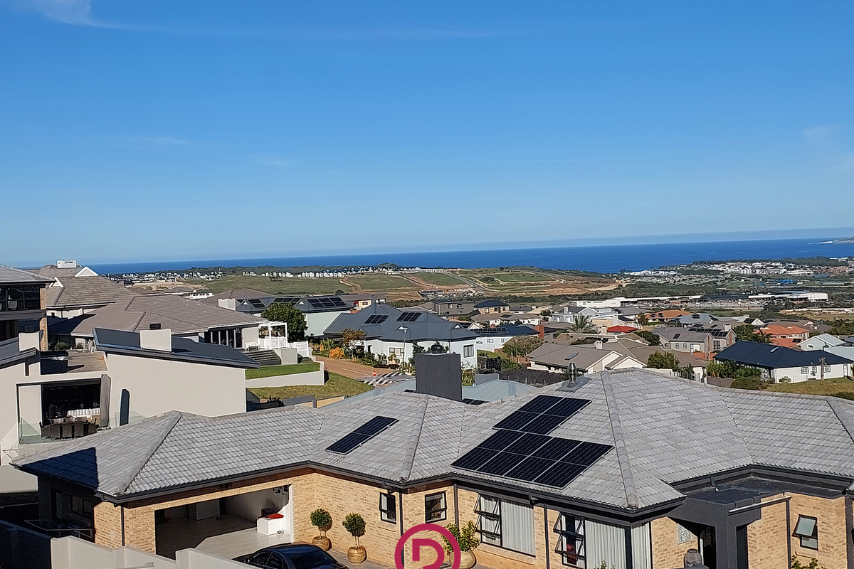 An elevated aerial view of a residential property featuring a tiled roof with solar panels, brick exterior, and a clear view of the surrounding neighborhood.