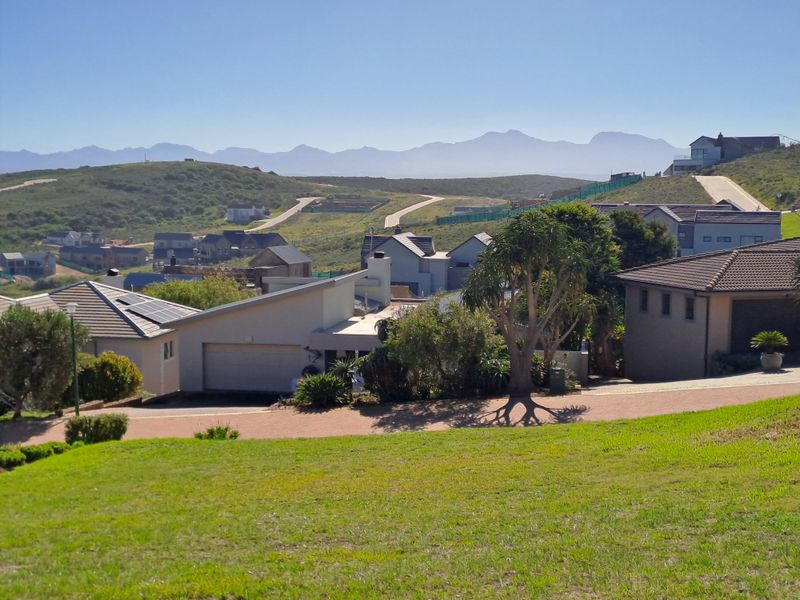 Elevated view overlooking a residential estate with surrounding hills and mountain range in the distance.