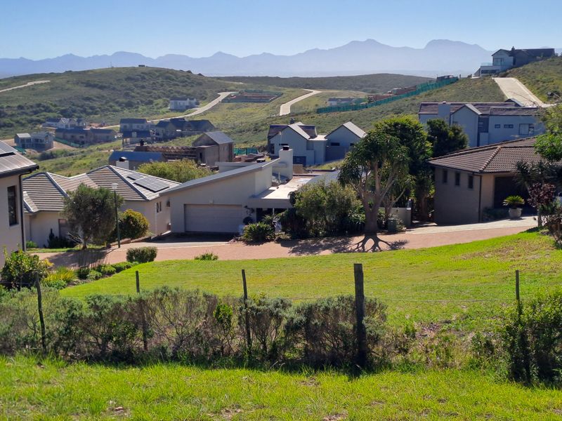 A scenic elevated view overlooking a residential estate with surrounding hills and mountain vistas in the distance.