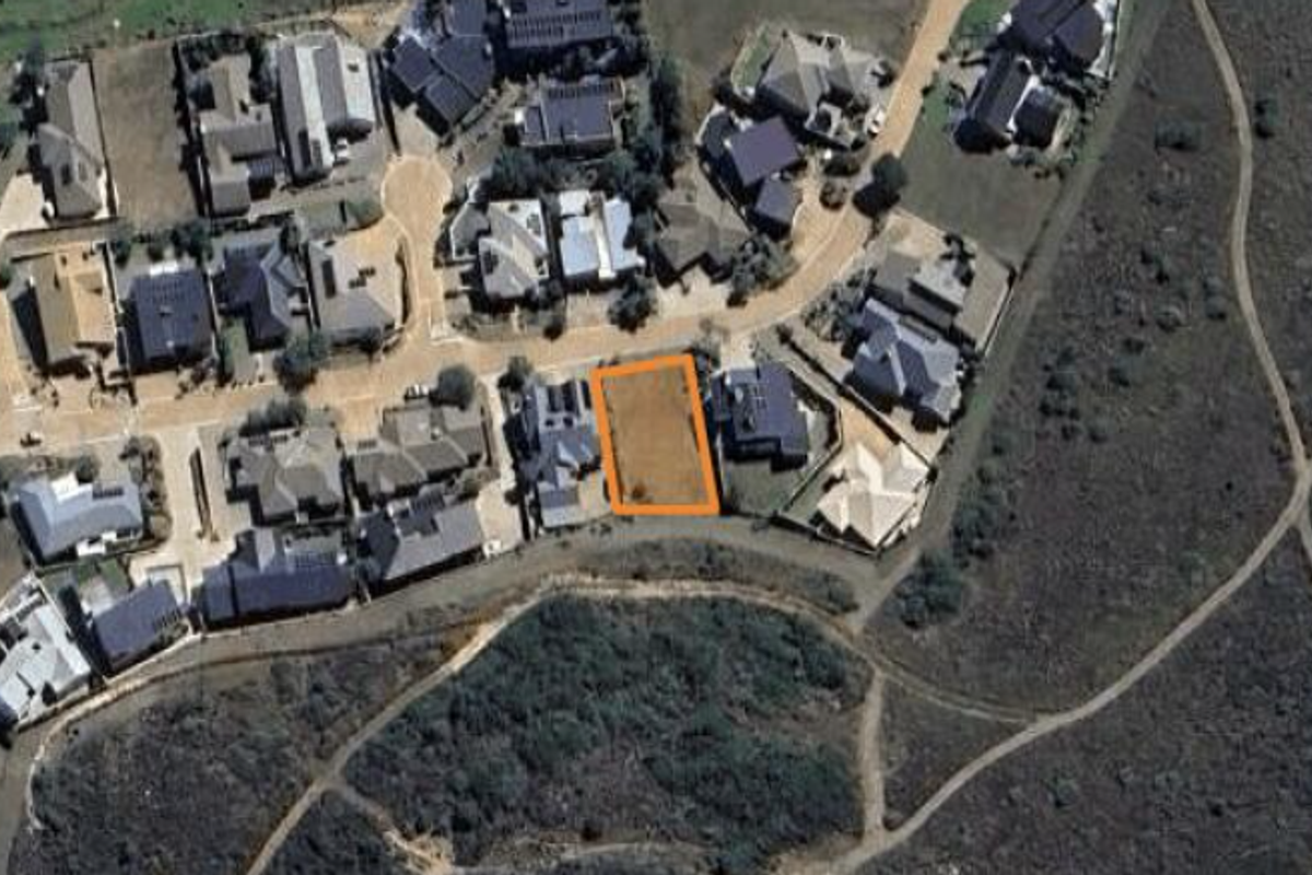 An aerial view of a vacant residential plot situated within an established suburban neighborhood.