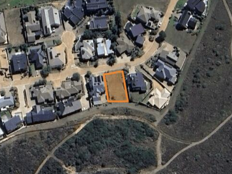 An aerial view of a vacant residential plot situated within an established suburban neighborhood.