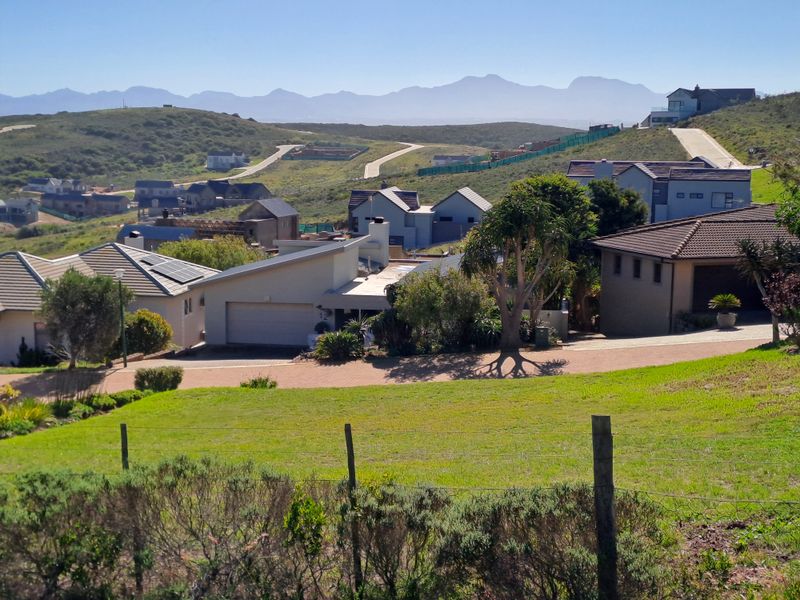 A scenic elevated view overlooking a residential estate with surrounding hills and mountain vistas in the distance.