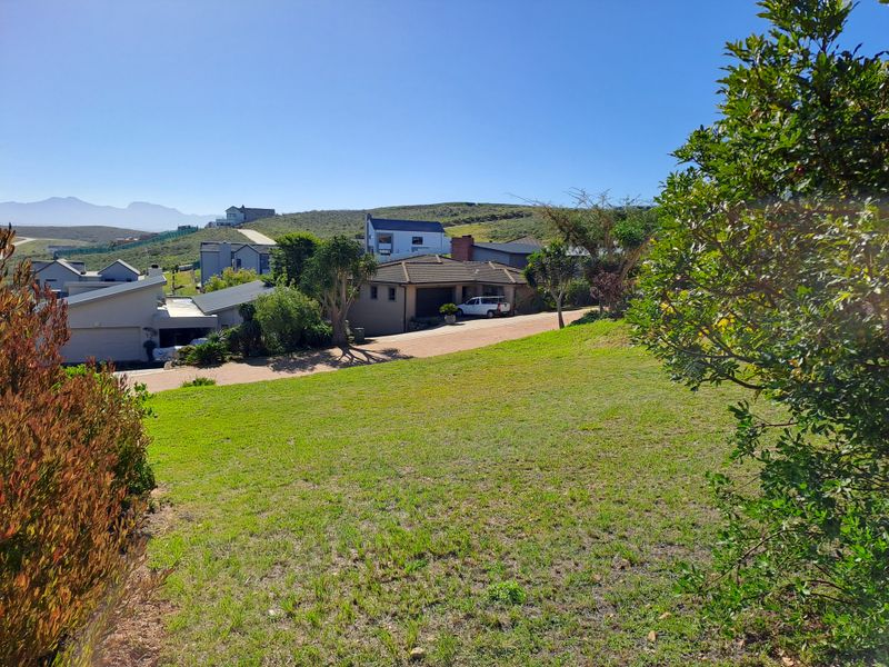 A view of the surrounding residential neighborhood and sloped landscape from the vacant residential property.