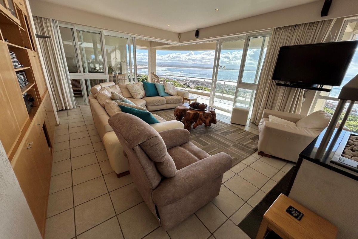 Spacious living room featuring tiled floors, built-in cabinetry, and expansive sliding glass doors opening to a balcony with panoramic ocean views.