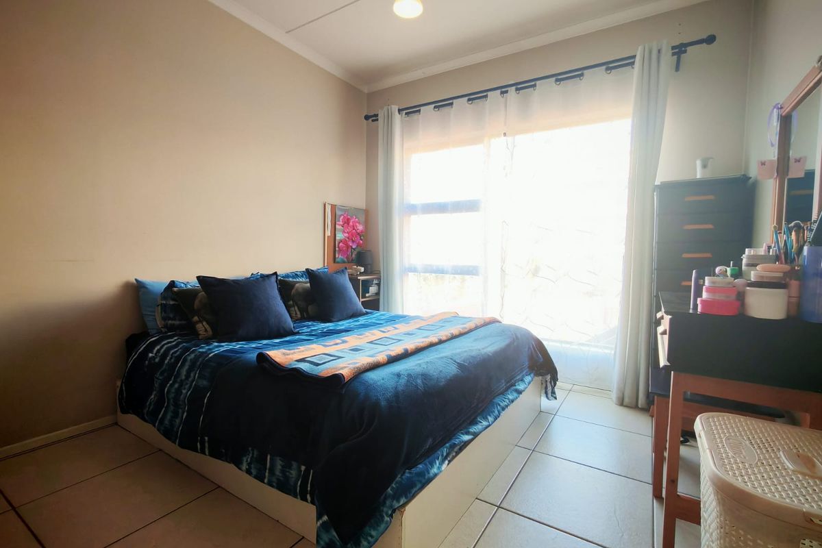 A bedroom featuring tiled flooring and a large sliding glass door that provides natural light.