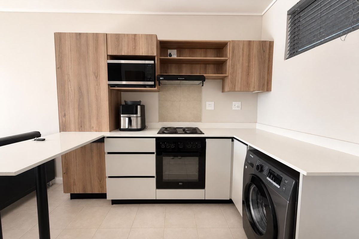 Modern kitchen featuring wood-grain and white cabinetry, quartz countertops, integrated appliances, and tiled flooring in a clean, contemporary layout.