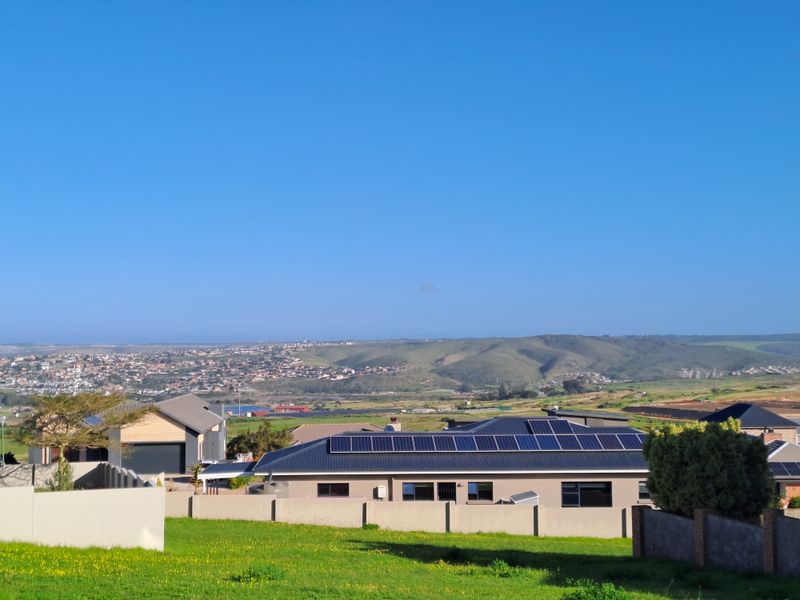 An elevated view overlooking a residential estate with surrounding hills and landscape in the distance.