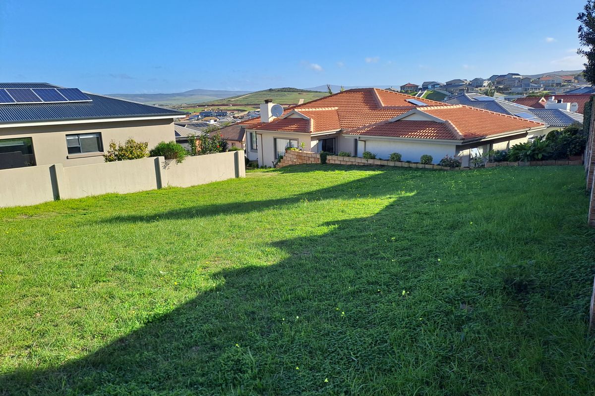 A view of a residential plot featuring a well-maintained lawn and boundary wall, situated within a developed neighborhood.