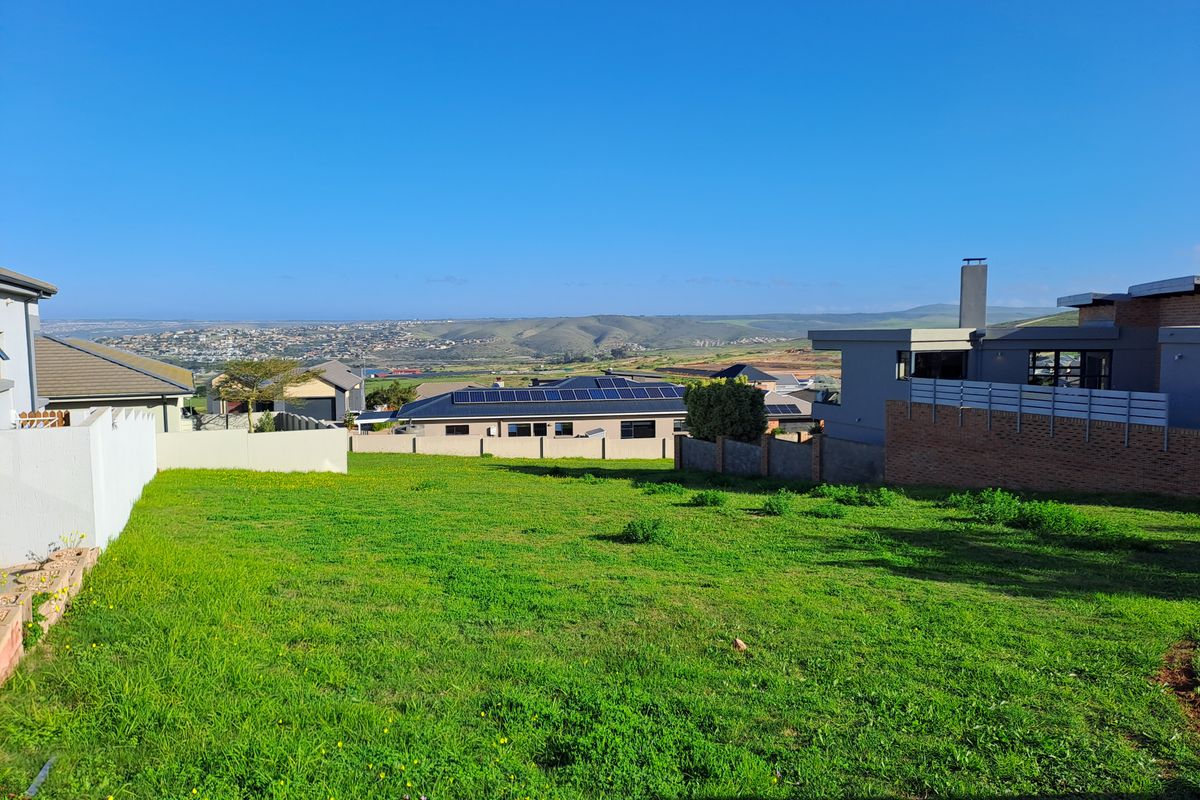 A clear view overlooking a residential neighborhood and surrounding landscape from a vacant residential plot.