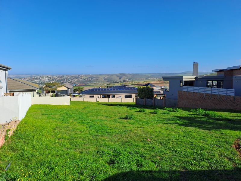 A clear view overlooking a residential neighborhood and surrounding landscape from a vacant residential plot.