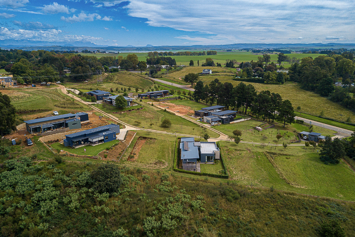 Aerial view of a residential development featuring modern dwellings set within a spacious, landscaped rural estate with established road access.