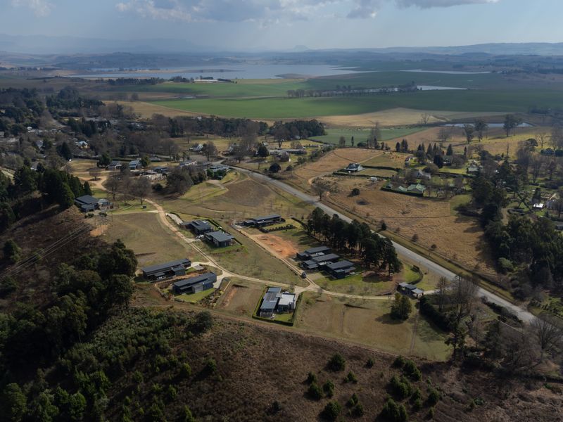 An aerial view of a residential estate development featuring modern homes set within a scenic, rural landscape with surrounding greenery and open fields.