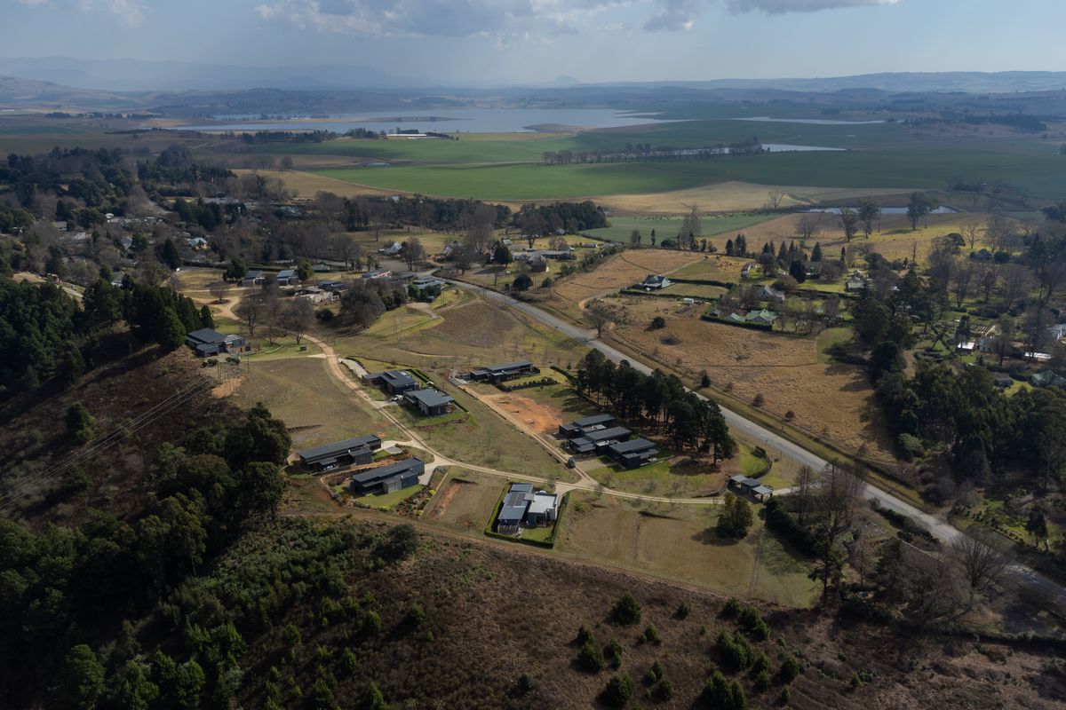 An aerial view of a residential estate development featuring modern homes set within a scenic, rural landscape with surrounding greenery and open fields.