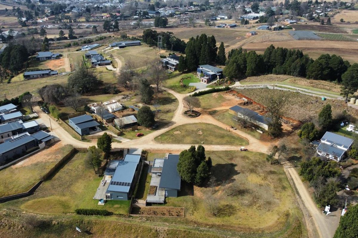 Aerial view of a residential estate featuring multiple dwellings, established landscaping, and internal gravel road infrastructure.