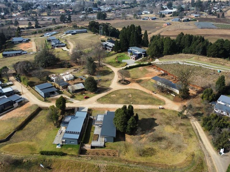 Aerial view of a residential estate featuring multiple dwellings, established landscaping, and internal gravel road infrastructure.