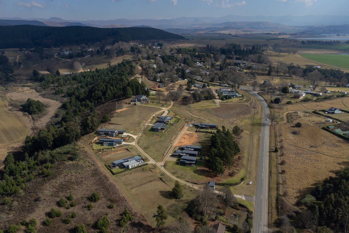 Aerial view of a residential estate development featuring modern homes, established landscaping, and surrounding rural landscape with road access.