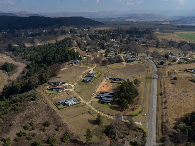Aerial view of a residential estate development featuring modern homes, established landscaping, and surrounding rural landscape with road access.